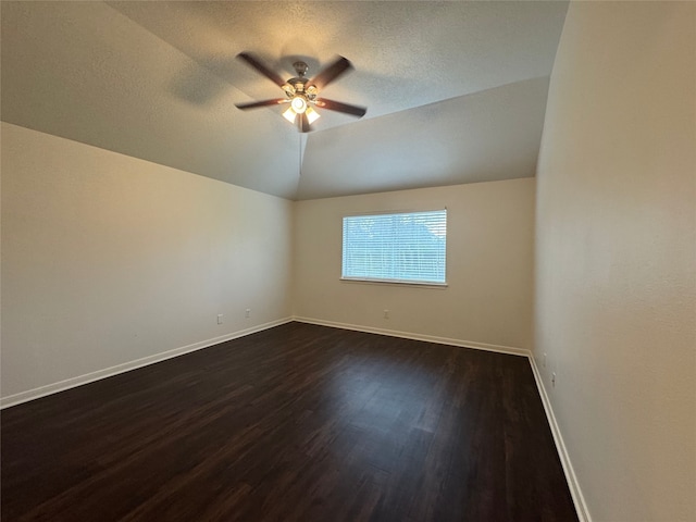 spare room with lofted ceiling, a textured ceiling, dark wood finished floors, baseboards, and ceiling fan