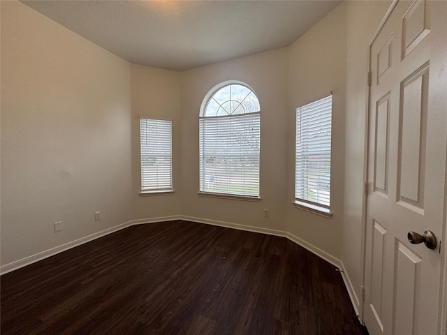 unfurnished room with baseboards and dark wood-style flooring