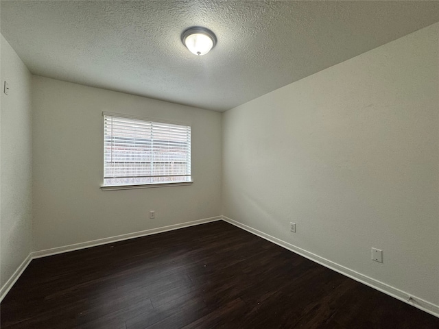 spare room featuring dark wood finished floors, a textured ceiling, and baseboards