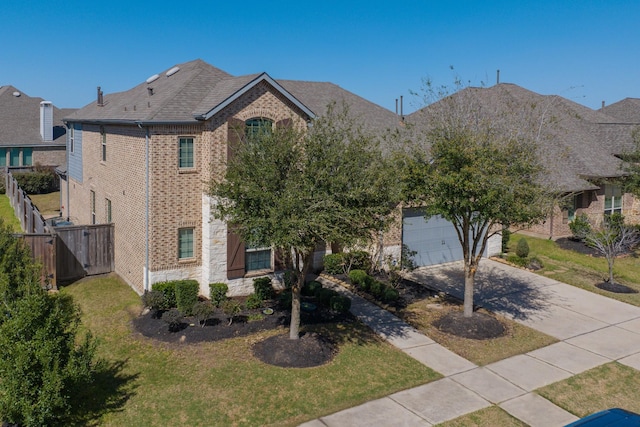 view of front facade featuring driveway, stone siding, fence, a front yard, and brick siding