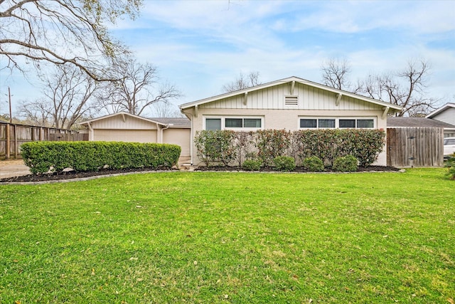 view of front of house with brick siding, a front yard, and fence