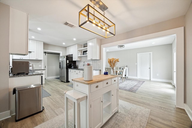 kitchen featuring visible vents, open shelves, tasteful backsplash, white cabinetry, and stainless steel fridge