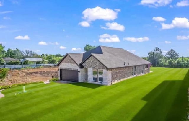 exterior space featuring an attached garage, a lawn, and stone siding