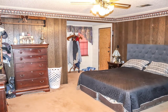 bedroom with wooden walls, carpet, visible vents, and a textured ceiling