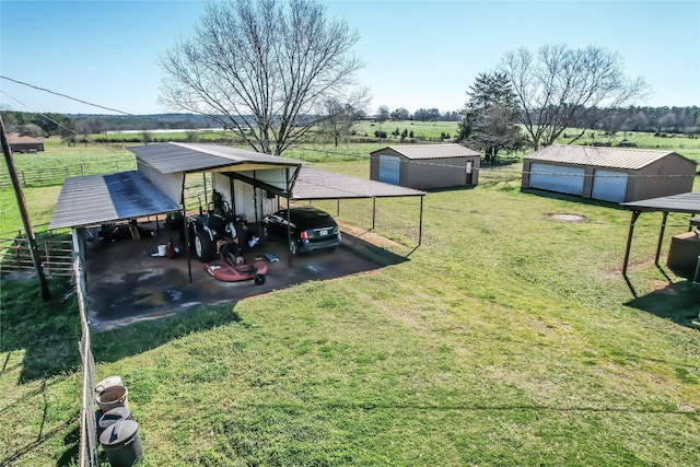 view of yard with a rural view, an outdoor structure, a carport, and fence