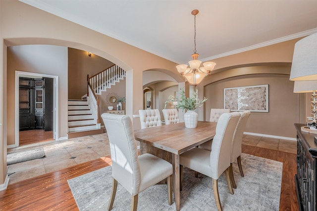 dining room featuring baseboards, a chandelier, stairway, light wood-type flooring, and arched walkways