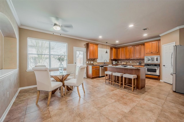 kitchen with brown cabinetry, stainless steel appliances, decorative backsplash, crown molding, and a center island