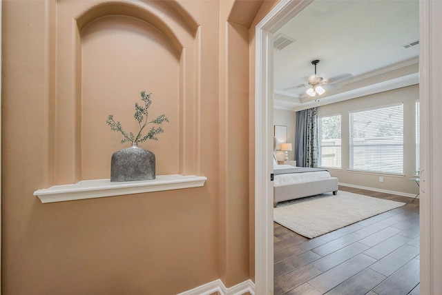 unfurnished bedroom with visible vents, a raised ceiling, baseboards, and wood finished floors