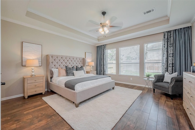 bedroom featuring baseboards, visible vents, dark wood finished floors, ornamental molding, and a raised ceiling