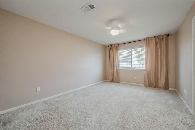 spare room featuring visible vents, light colored carpet, baseboards, and ceiling fan