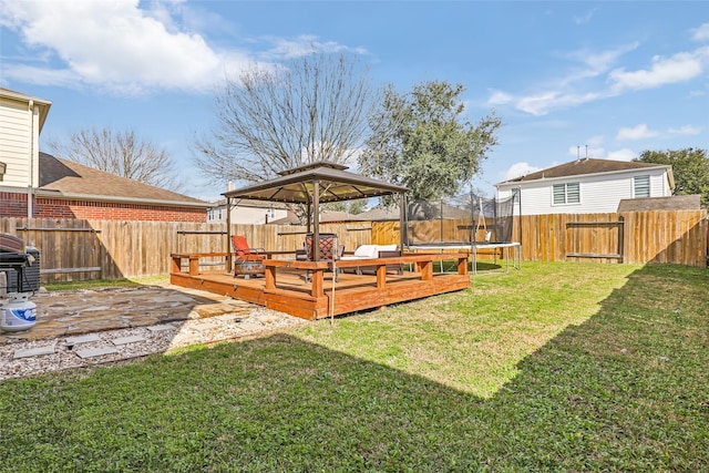 view of yard with a patio area, a trampoline, a fenced backyard, and a wooden deck