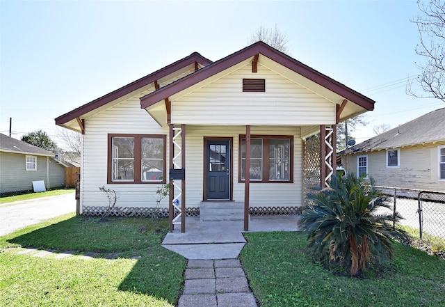 bungalow-style house with covered porch, a front lawn, and fence