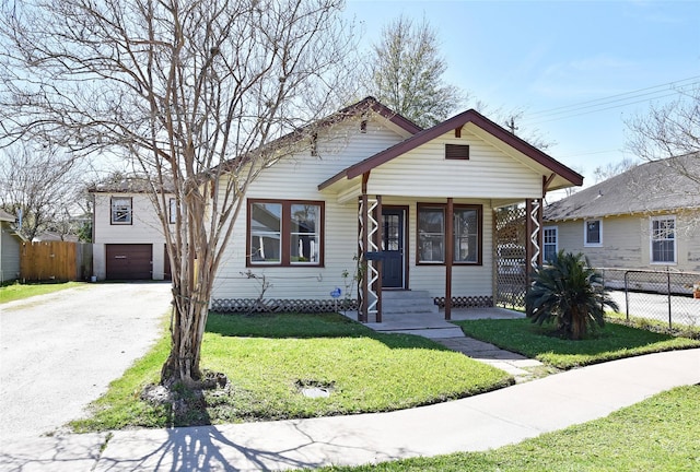 view of front of house with a garage, driveway, a front lawn, and fence