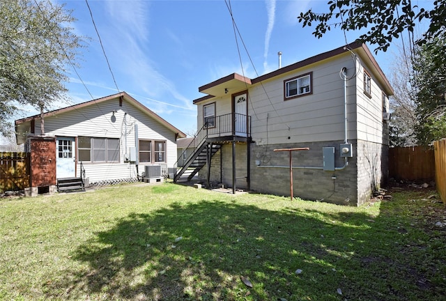 rear view of house with entry steps, central AC unit, a yard, and fence