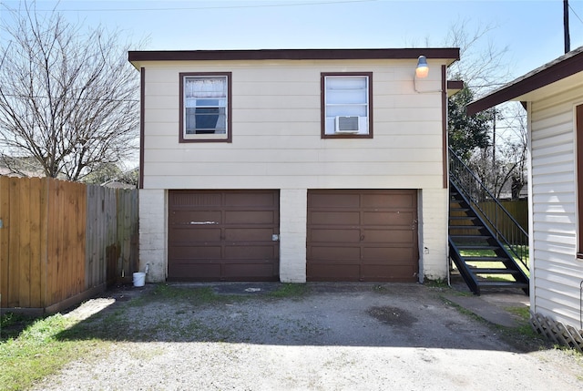 exterior space featuring stairway, a garage, cooling unit, and fence