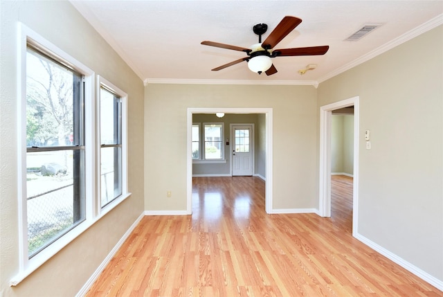 empty room featuring visible vents, baseboards, light wood-type flooring, ornamental molding, and a ceiling fan