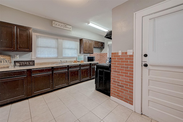 kitchen with light tile patterned floors, stainless steel microwave, light countertops, and a sink