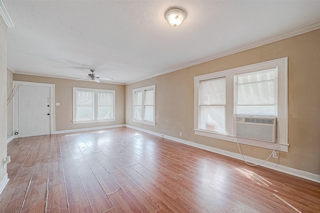 unfurnished room with wood finished floors, baseboards, ceiling fan, ornamental molding, and a textured ceiling