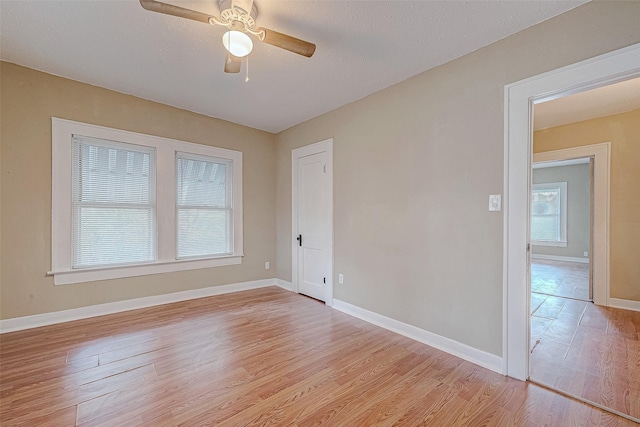 empty room with ceiling fan, light wood-type flooring, and baseboards