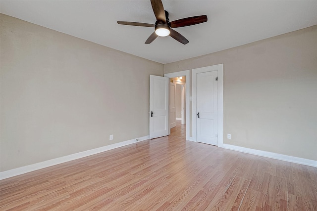 spare room with baseboards, a ceiling fan, and light wood finished floors