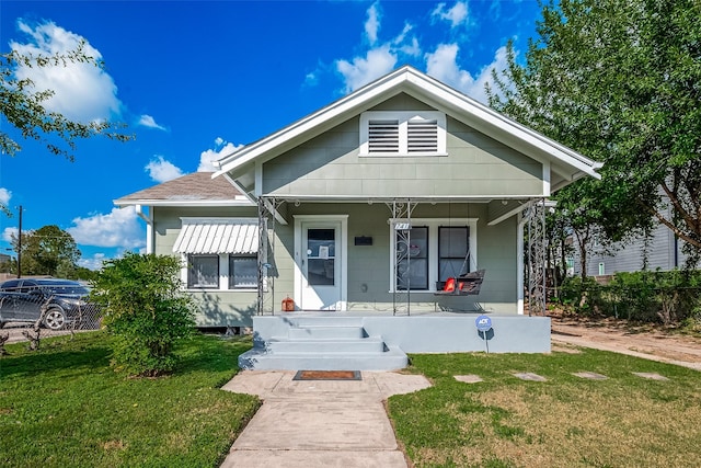 view of front facade featuring a front yard, covered porch, and roof with shingles