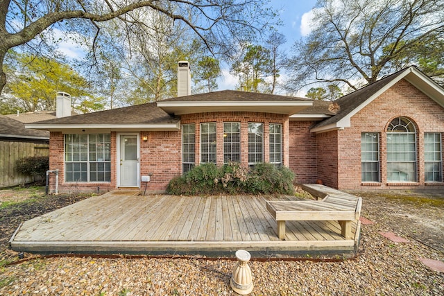 back of house featuring a wooden deck, brick siding, and a chimney