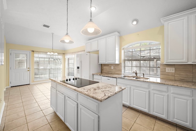 kitchen featuring a sink, white appliances, a kitchen island, and vaulted ceiling