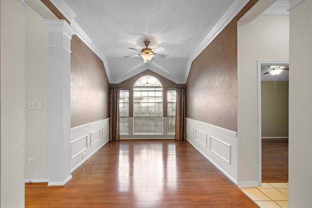 empty room featuring lofted ceiling, a ceiling fan, and a decorative wall