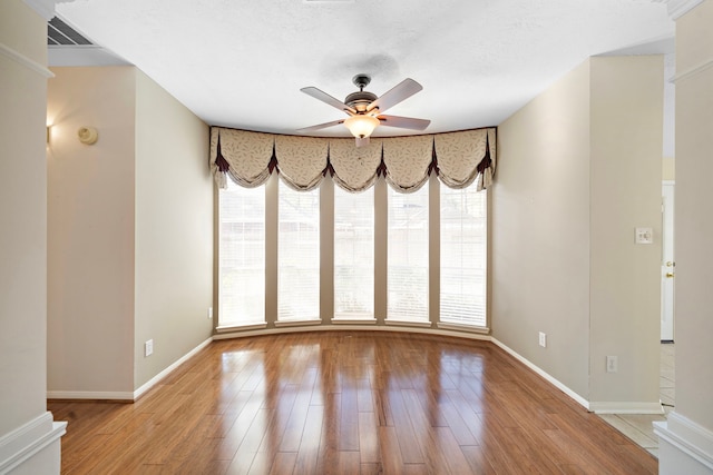 empty room with visible vents, baseboards, light wood-style floors, and a ceiling fan