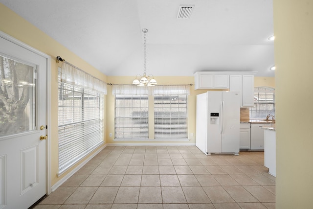 unfurnished dining area featuring visible vents, an inviting chandelier, lofted ceiling, light tile patterned flooring, and a sink