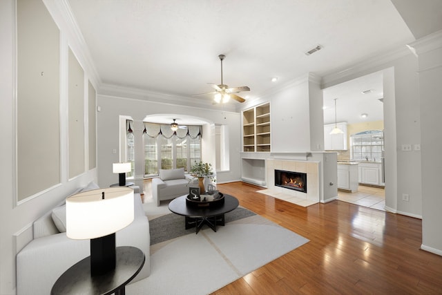 living area featuring a ceiling fan, light wood finished floors, and a healthy amount of sunlight