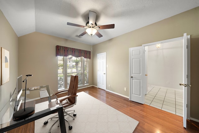 office with visible vents, baseboards, lofted ceiling, wood finished floors, and a ceiling fan