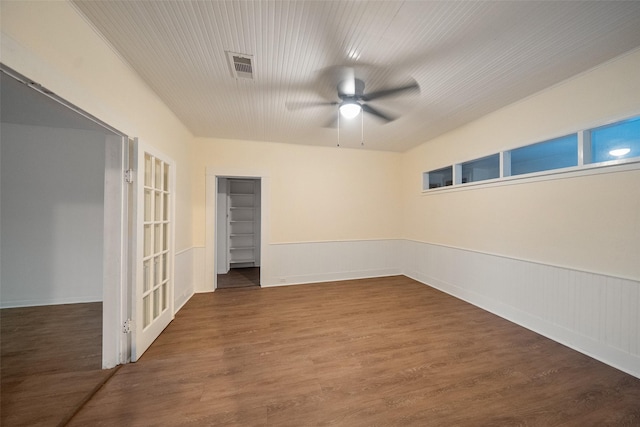 spare room with a wainscoted wall, wood finished floors, visible vents, and a ceiling fan