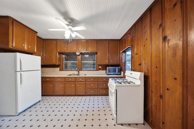 kitchen featuring a sink, white appliances, brown cabinetry, light countertops, and light floors