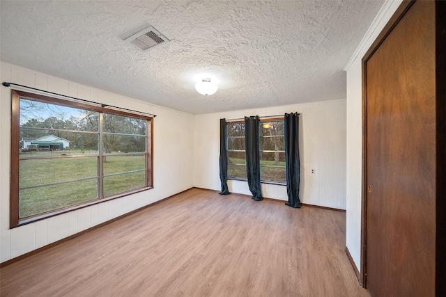 spare room featuring visible vents, light wood-style floors, and a textured ceiling