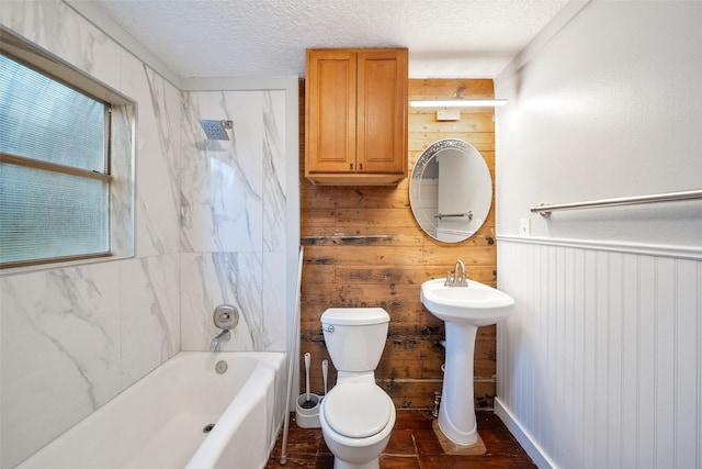 bathroom featuring wooden walls, a wainscoted wall, a sink, a textured ceiling, and toilet