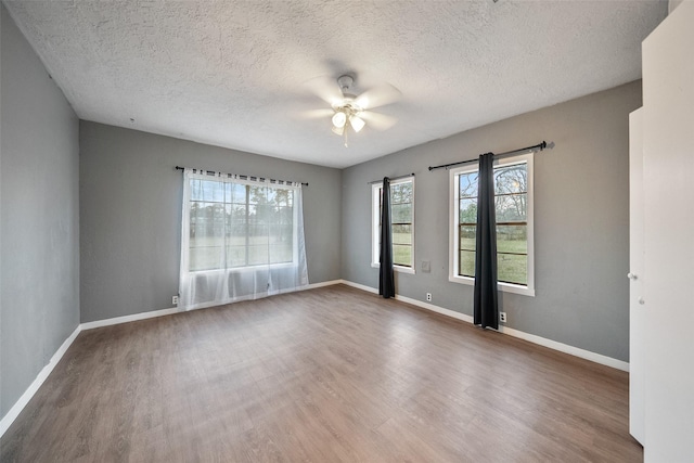 empty room with ceiling fan, baseboards, a textured ceiling, and wood finished floors