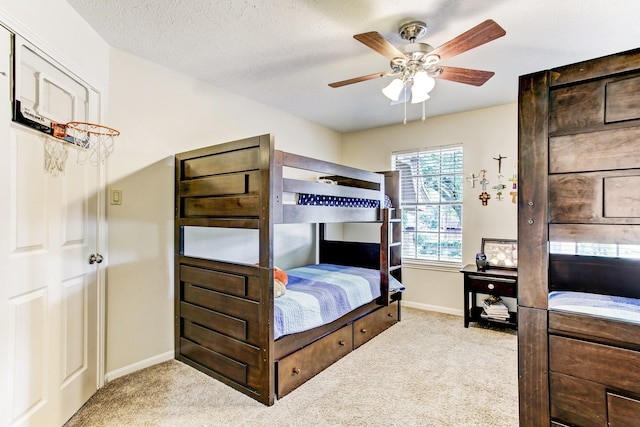 bedroom featuring a ceiling fan, carpet, baseboards, and a textured ceiling