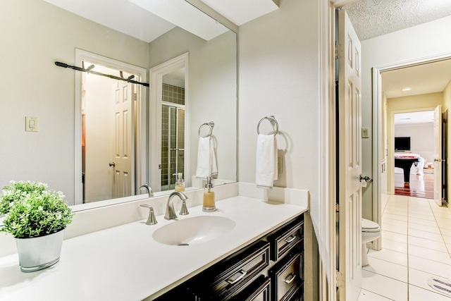 bathroom with a textured ceiling, toilet, vanity, and tile patterned flooring