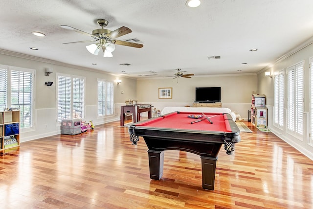 playroom featuring a textured ceiling, light wood-style floors, visible vents, and ornamental molding