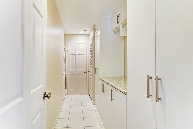 hall featuring light tile patterned flooring and stacked washer and clothes dryer