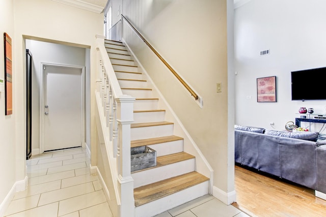 stairs with tile patterned flooring, crown molding, baseboards, and visible vents