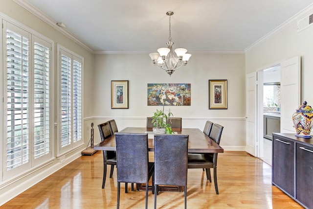 dining area with visible vents, an inviting chandelier, light wood-style flooring, and ornamental molding