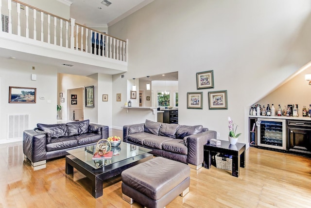 living room with visible vents, a dry bar, light wood-style floors, and ornamental molding