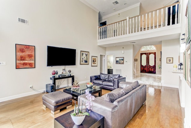 living area with visible vents, baseboards, ornamental molding, and light wood finished floors