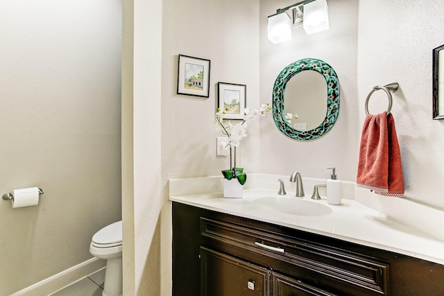 half bath with tile patterned flooring, toilet, vanity, and baseboards