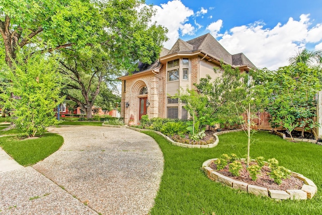 view of front facade featuring brick siding, concrete driveway, a front yard, and a shingled roof