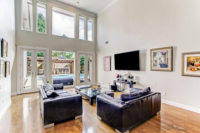 living room with baseboards, french doors, light wood-type flooring, and ornamental molding