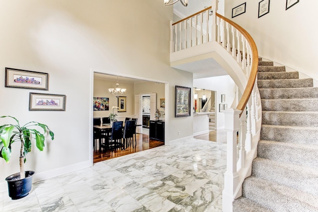 interior space with baseboards, stairs, a high ceiling, an inviting chandelier, and marble finish floor