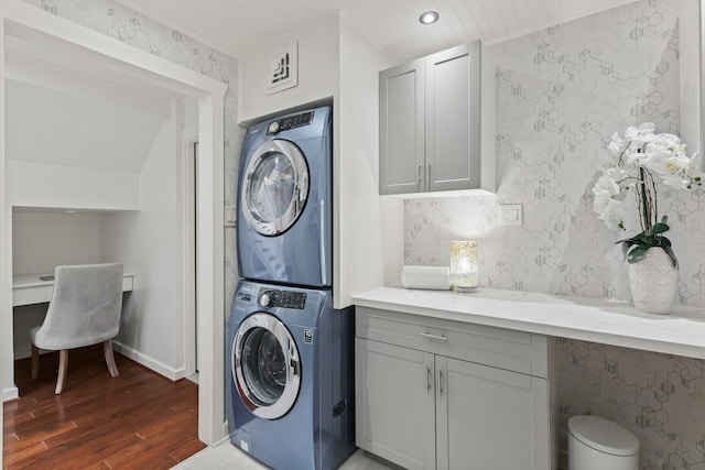 washroom with wood finished floors, stacked washing maching and dryer, wallpapered walls, laundry area, and recessed lighting